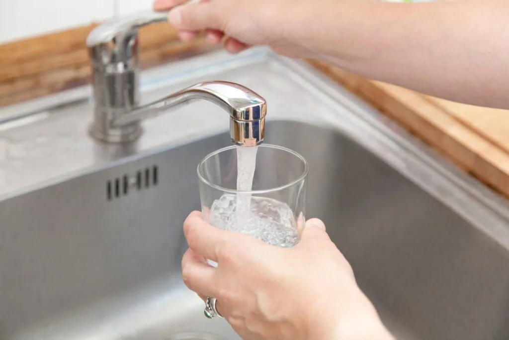 a person turning on faucet showing water testing services in NY and CT